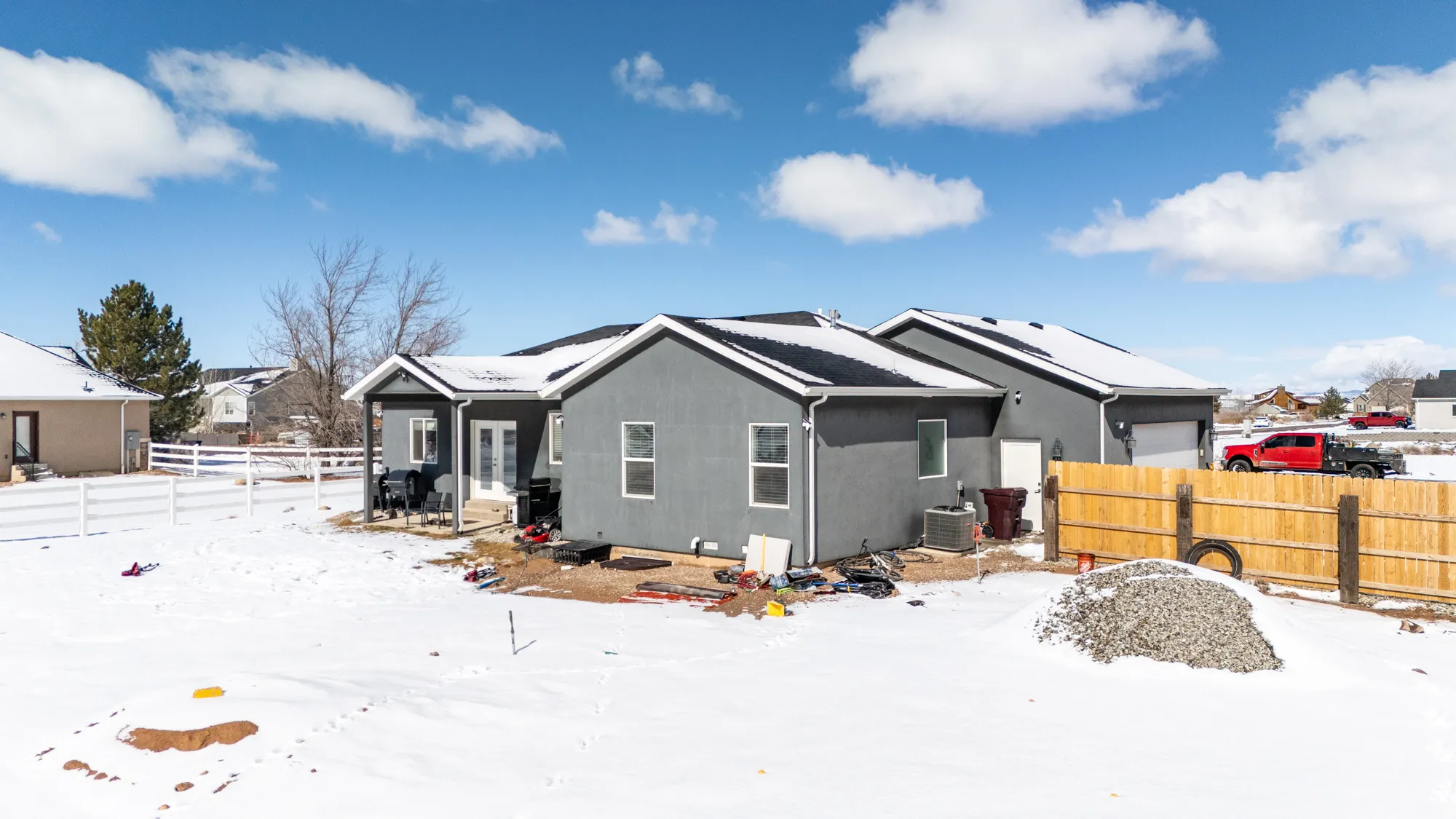 Snow covered property featuring stucco siding, a garage, and solar panels