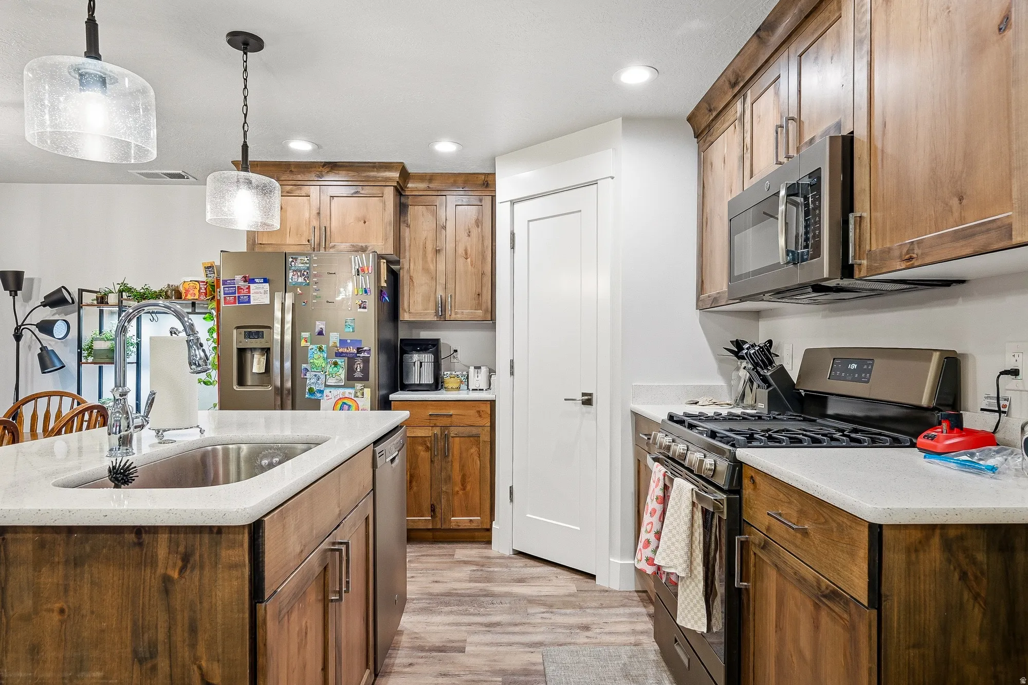 Kitchen with stainless steel appliances, pendant lighting, light wood-style flooring, and wood finish cabinets