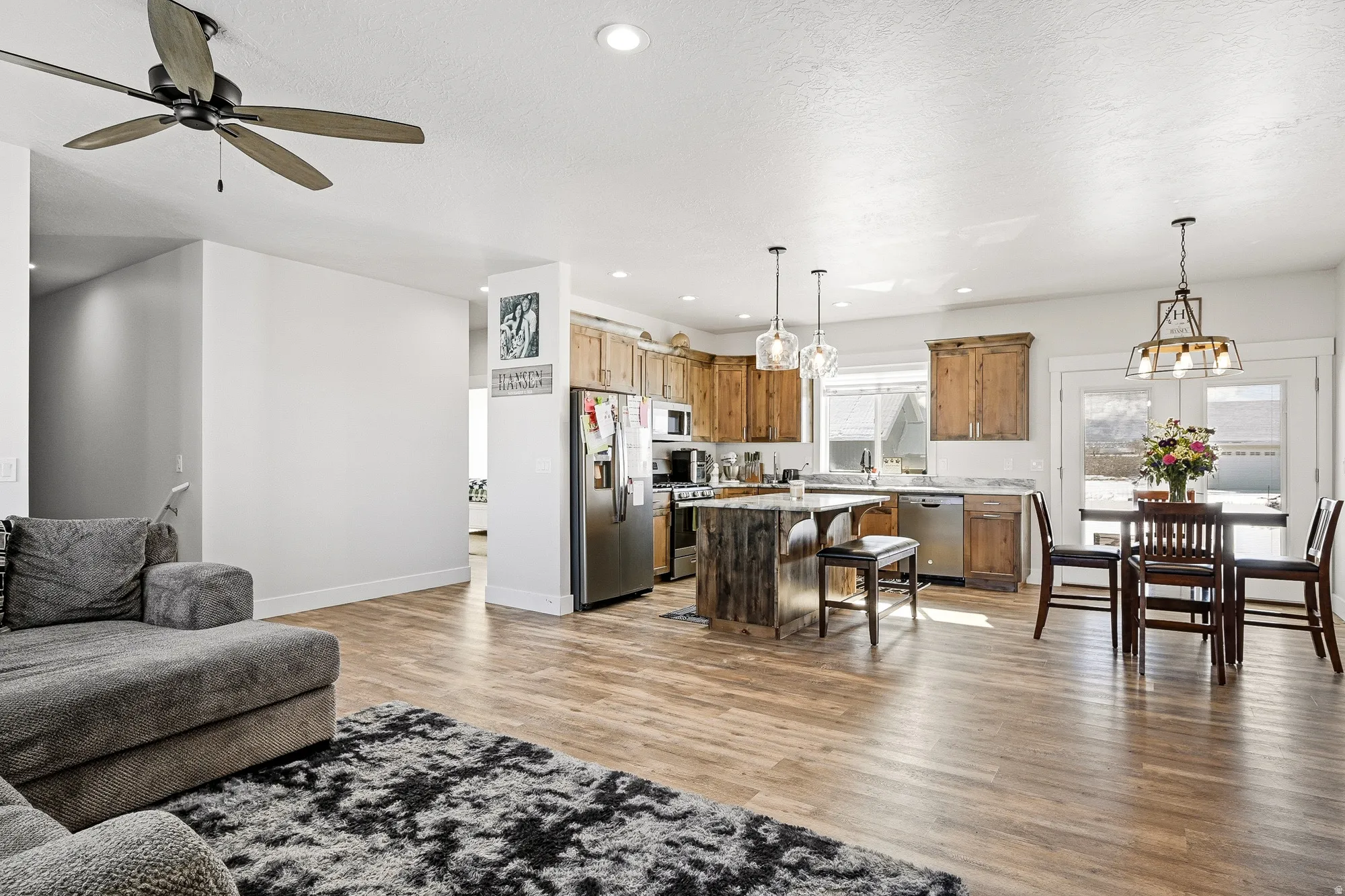 Living area with light wood-type flooring, ceiling fan, and a chandelier