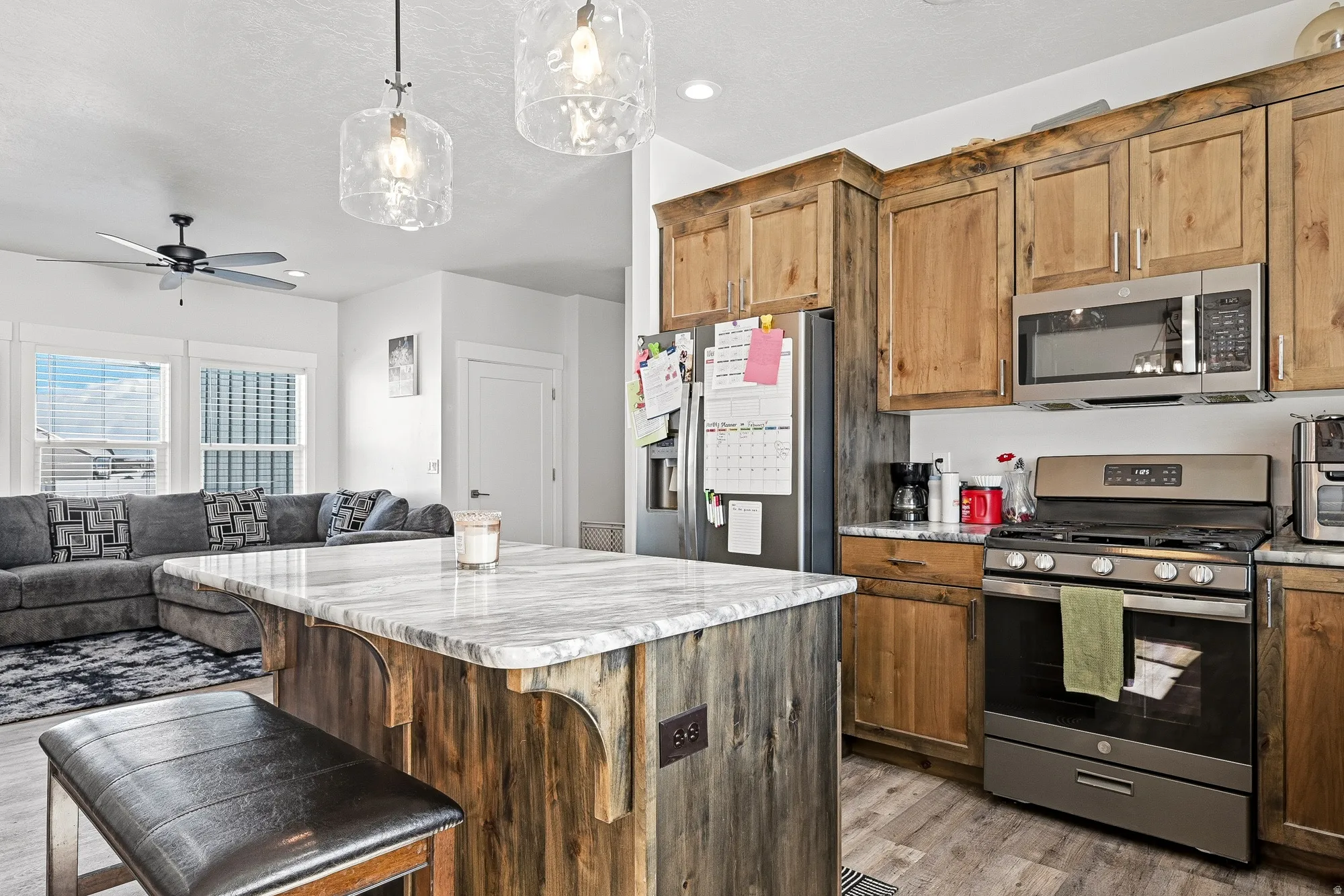 Kitchen with stainless steel appliances, open floor plan, pendant lighting, a ceiling fan, and wood finish cabinets
