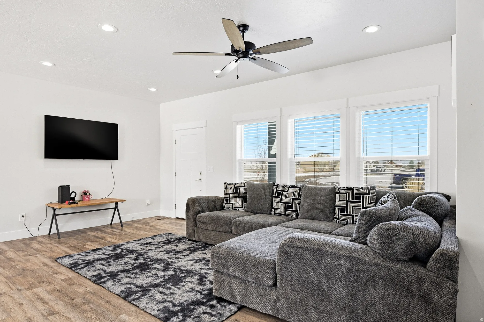 Living area with ceiling fan, wood finished floors, and recessed lighting