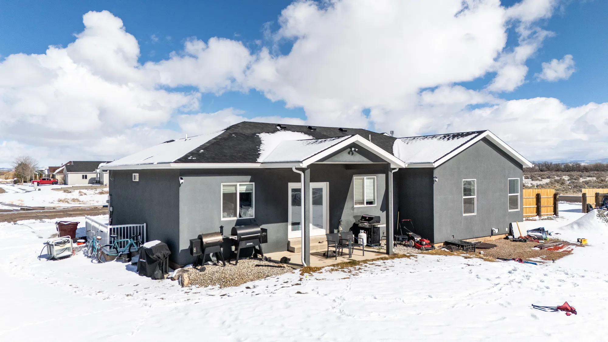 Snow covered rear of property with a patio and stucco siding