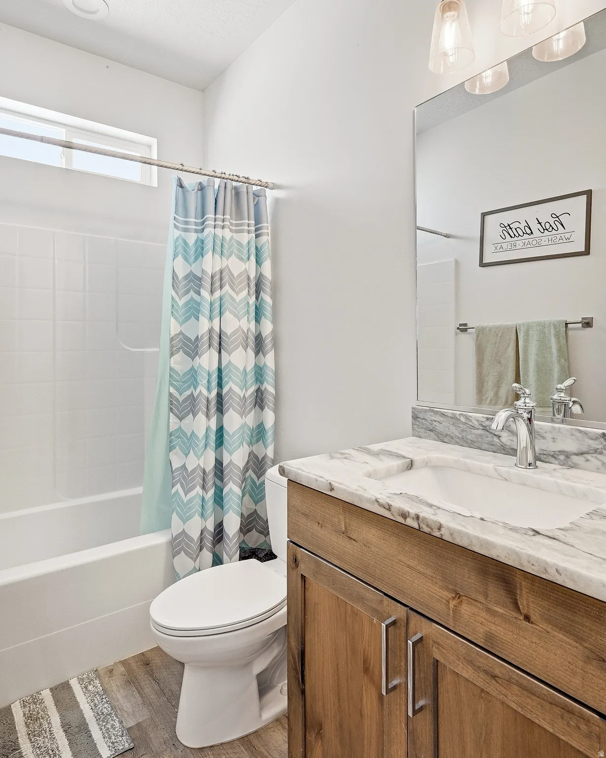 Full bath with vanity, shower / tub combo, and light wood-type flooring