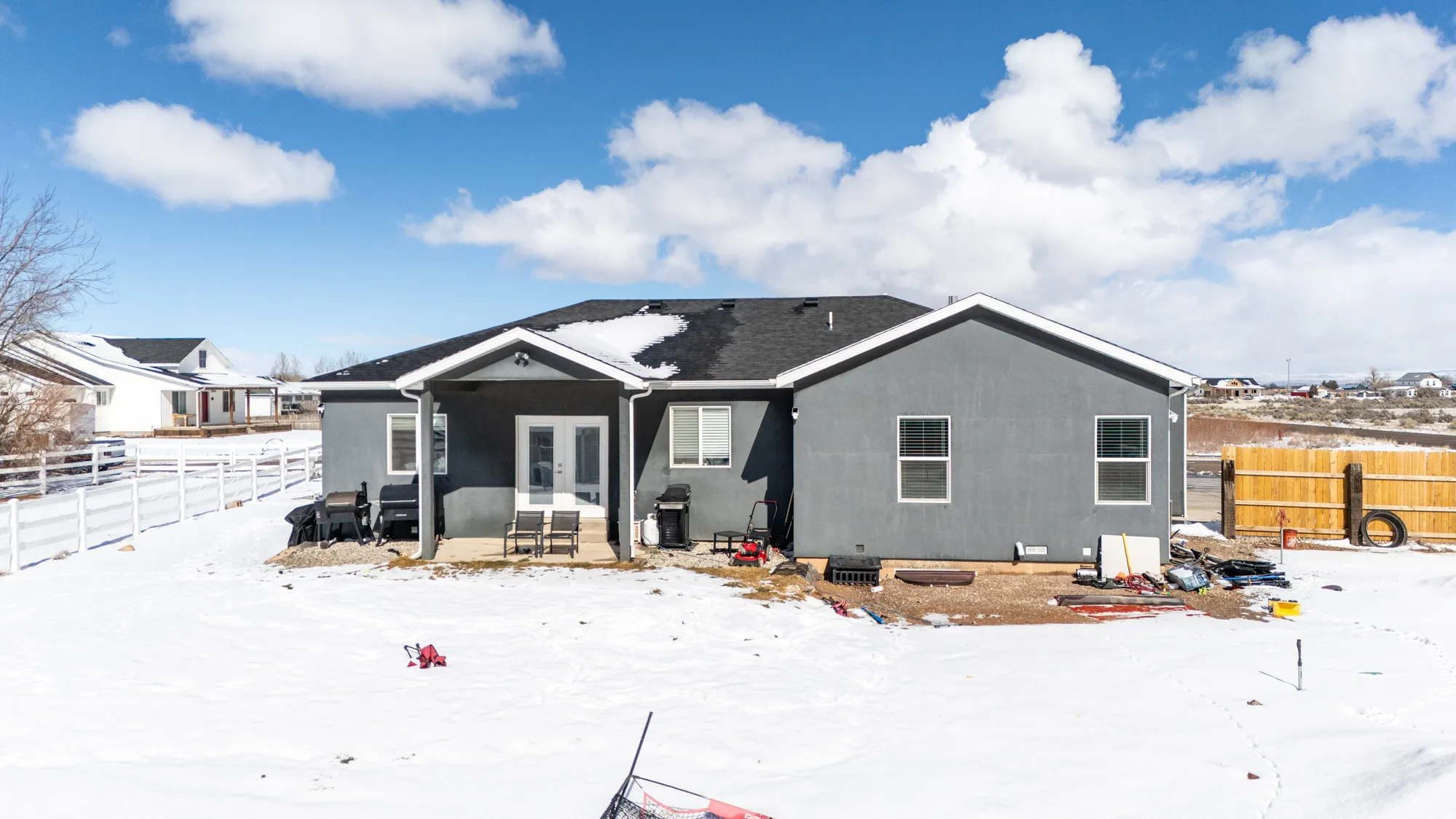 Snow covered back of property with a patio, french doors, and stucco siding