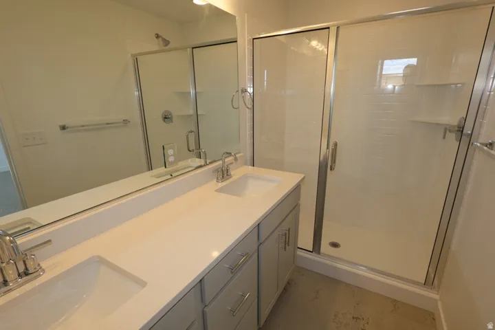 Full bathroom featuring double vanity, a shower stall, and light tile patterned floors