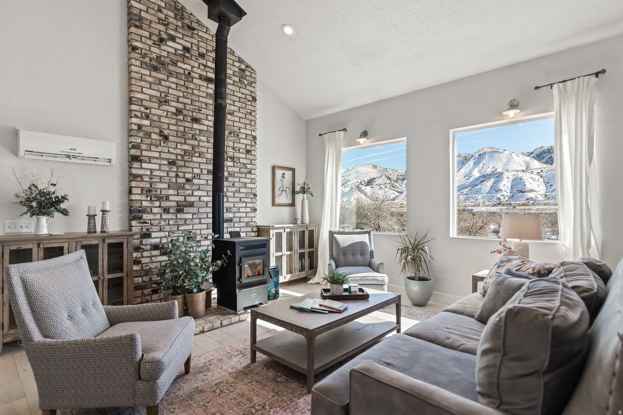 Living area featuring a wood stove, a mountain view, wood-type flooring, and a high textured ceiling
