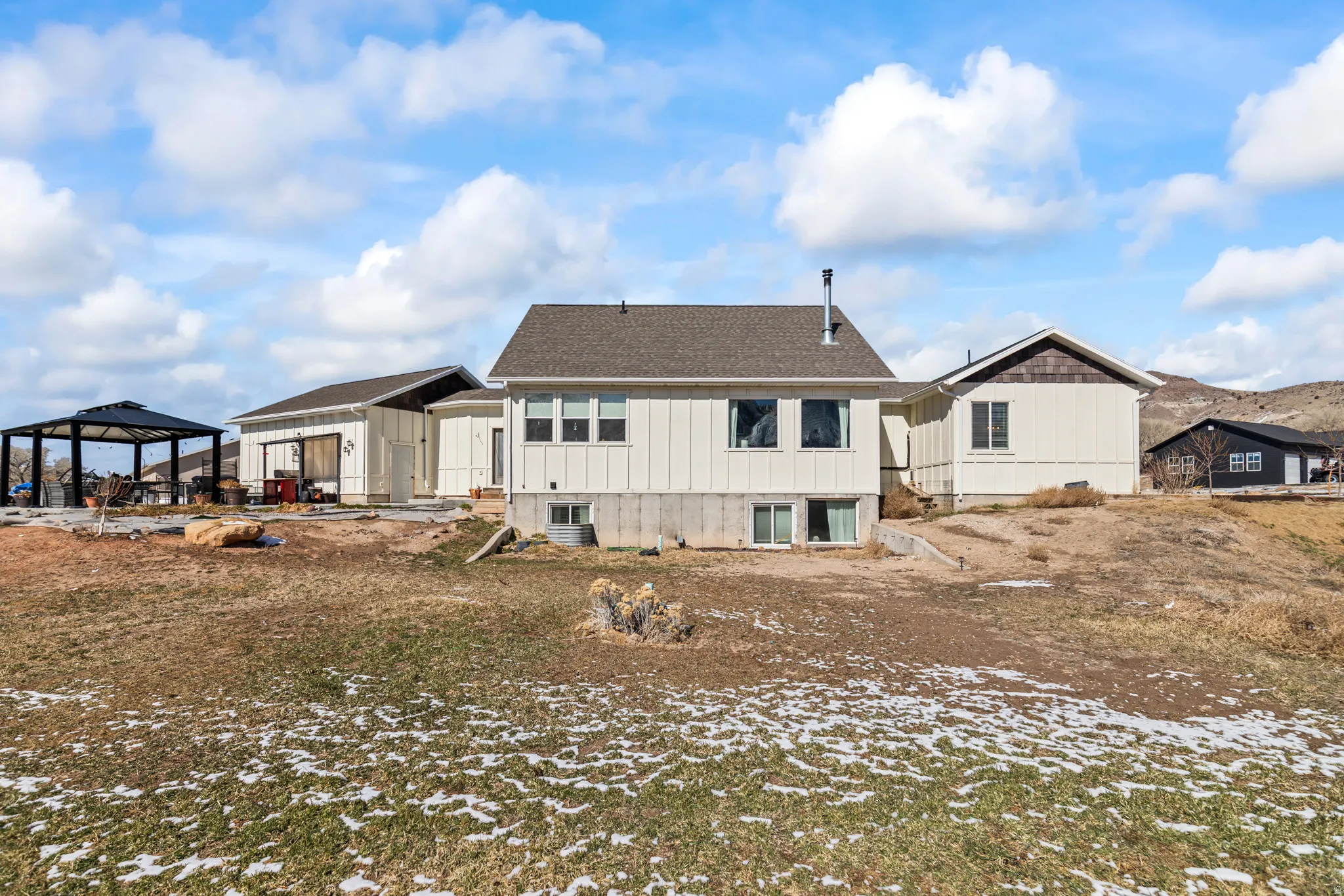 Back of property with a patio area, board and batten siding, and a gazebo