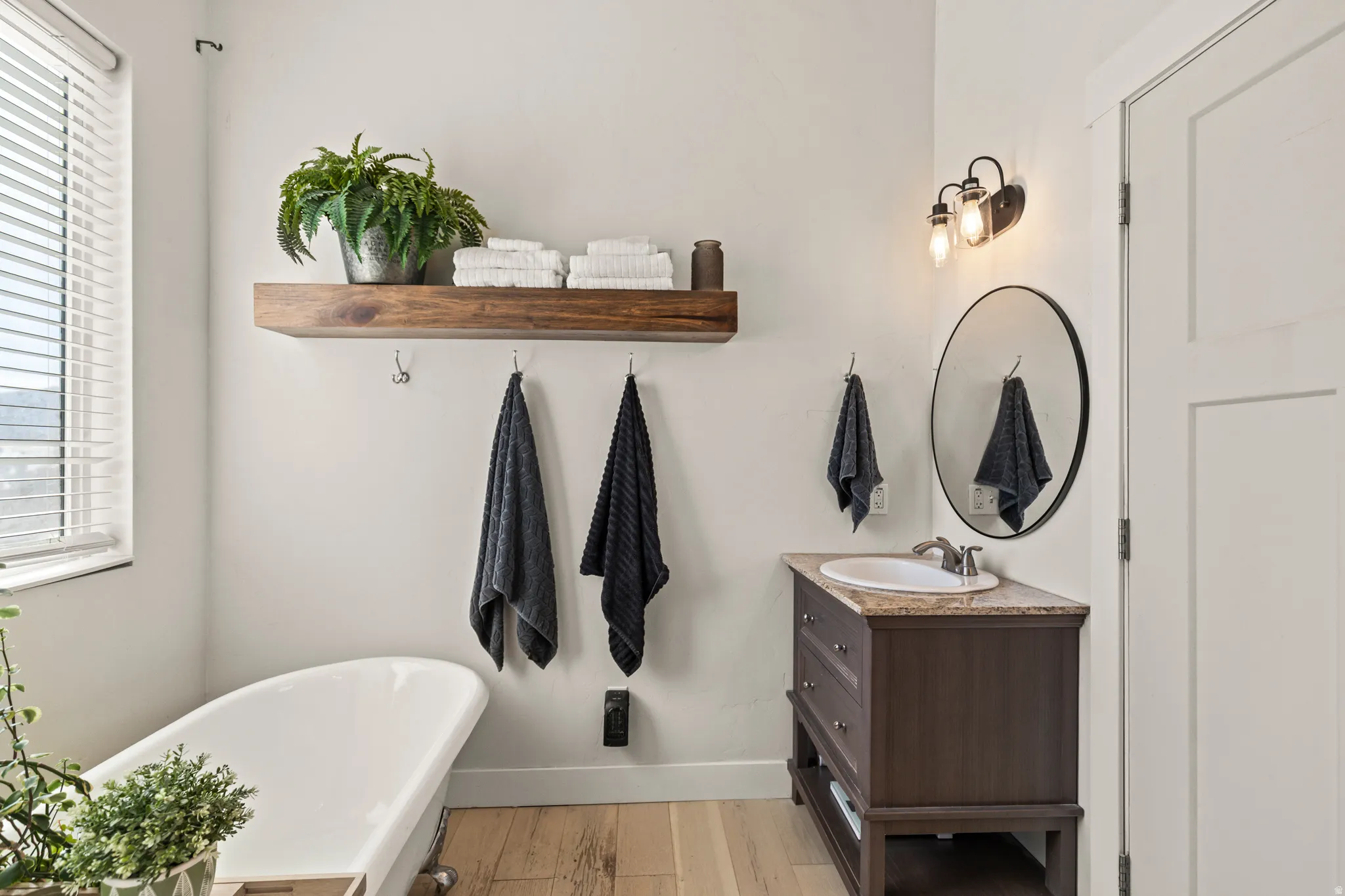 Bathroom with vanity, a soaking tub, healthy amount of natural light, and light wood finished floors