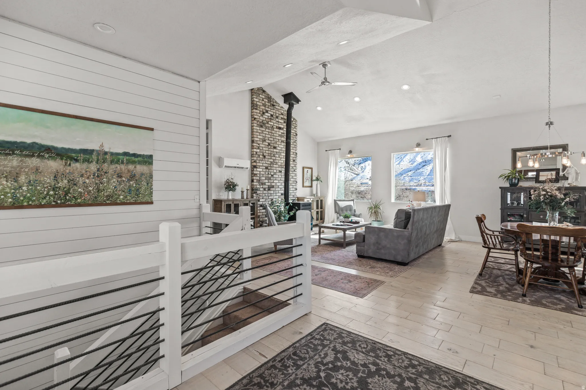 Living area featuring a wood stove, light wood-style flooring, lofted ceiling, a ceiling fan, and wooden walls