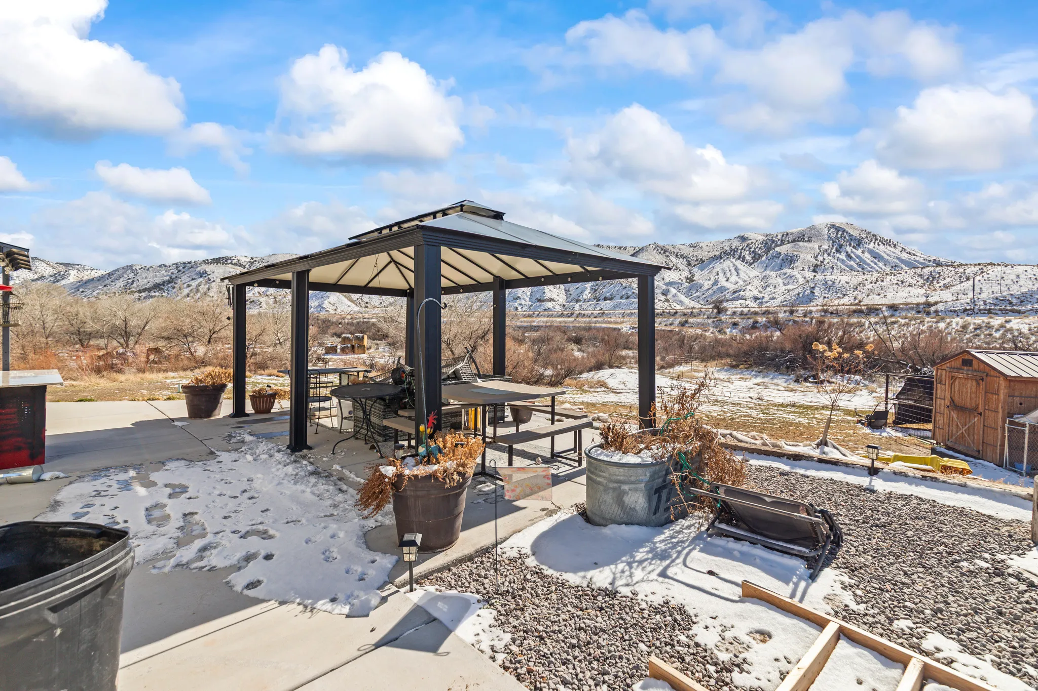 Snow covered patio with a patio, a mountain view, a gazebo, and a storage unit