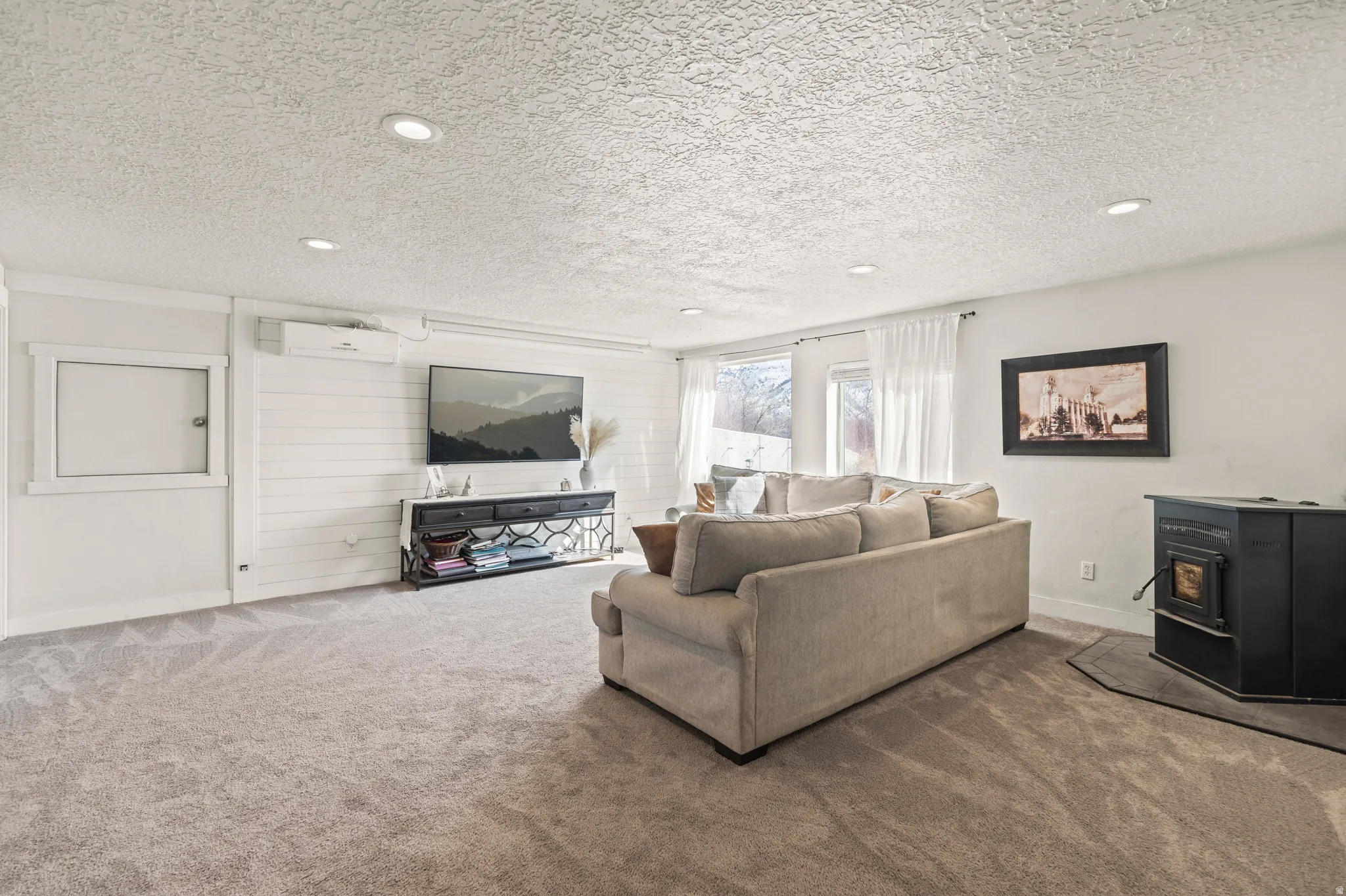 Living area with a wood stove, carpet floors, and a textured ceiling