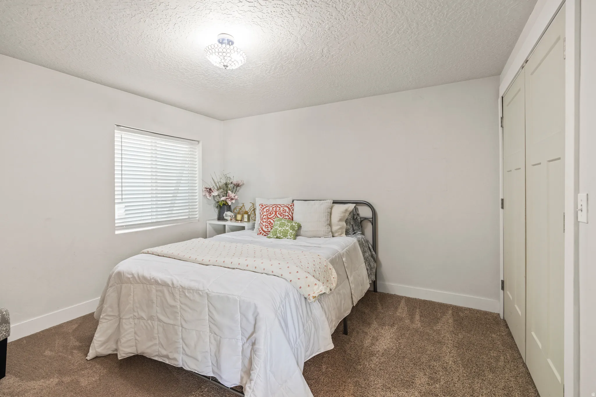 Bedroom featuring dark carpet, a textured ceiling, and a closet