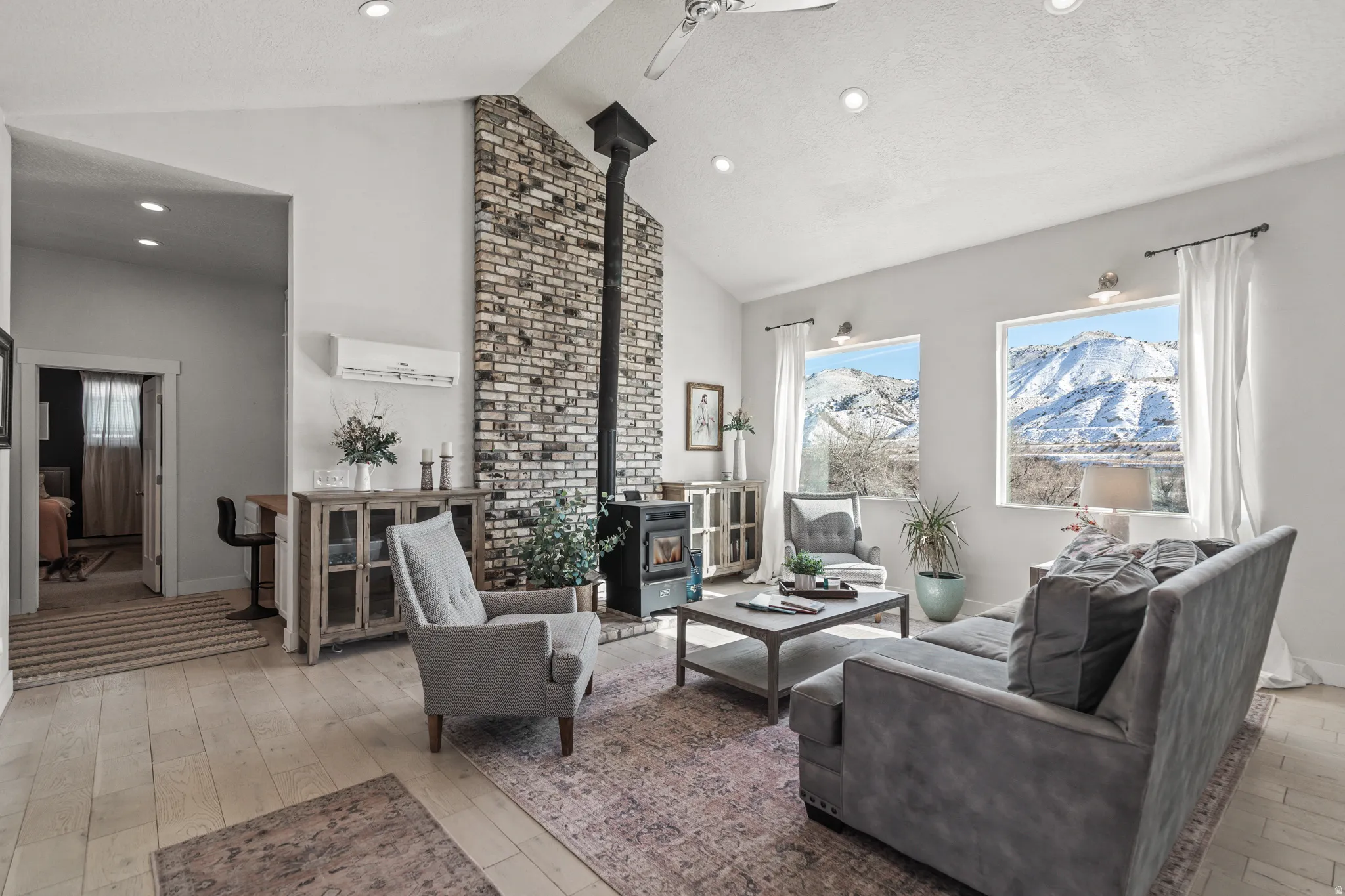 Living room featuring a wood stove, light wood-style floors, a ceiling fan, recessed lighting, and a high textured ceiling
