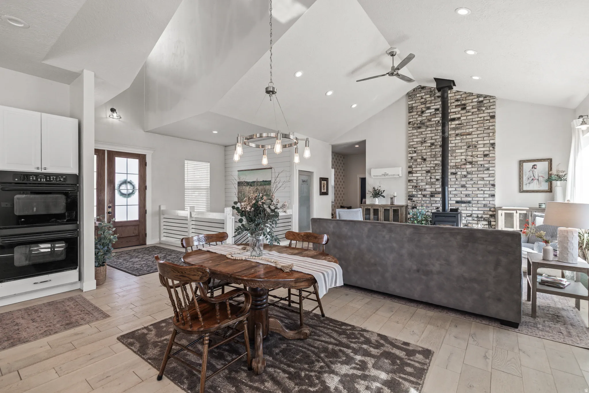 Dining area featuring a wood stove, a high ceiling, light wood finished floors, and a ceiling fan