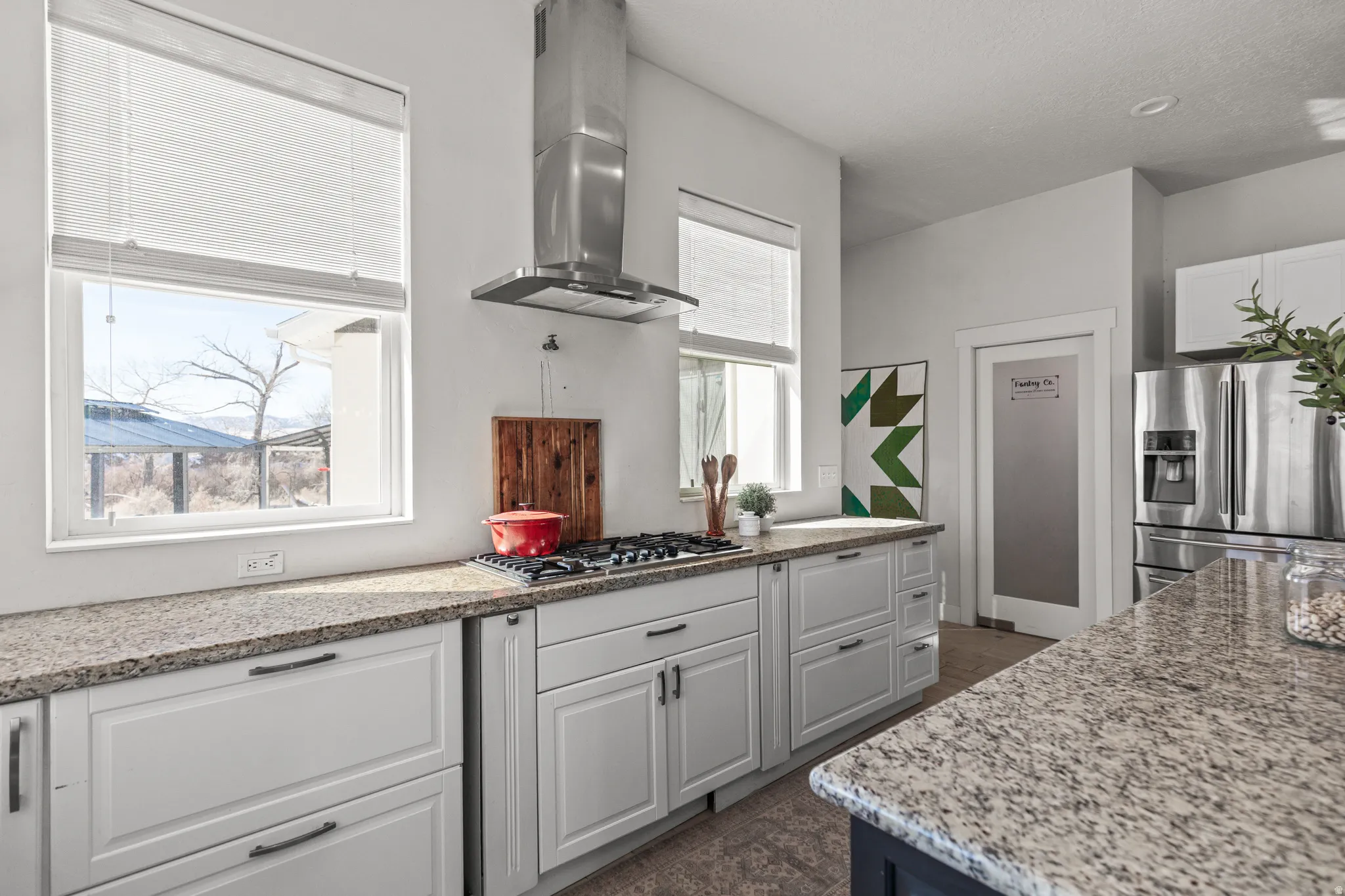 Two tone kitchen featuring light stone counters, stainless steel appliances, and two tone color scheme