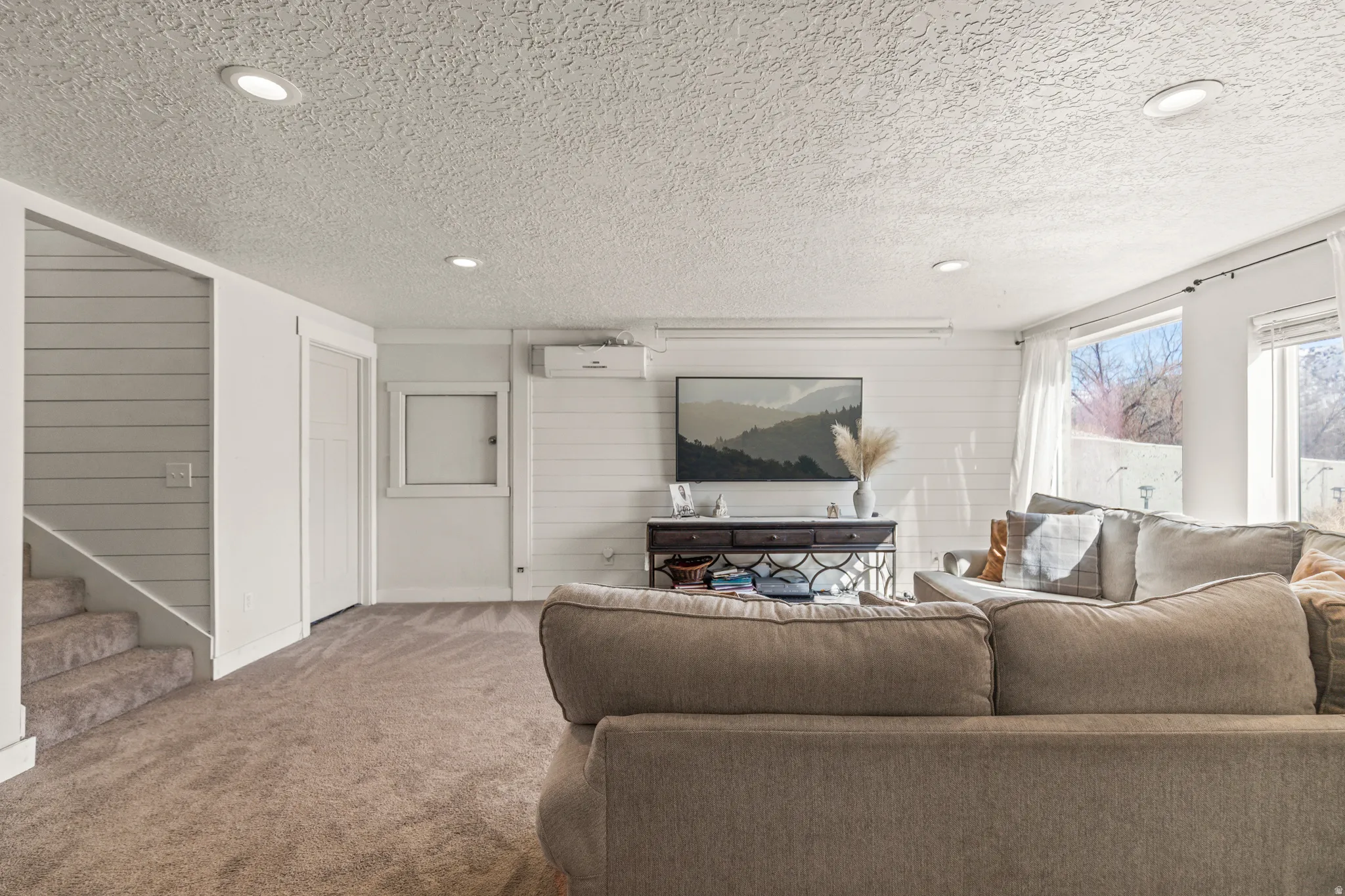 Living room featuring carpet flooring, wood walls, recessed lighting, and a textured ceiling