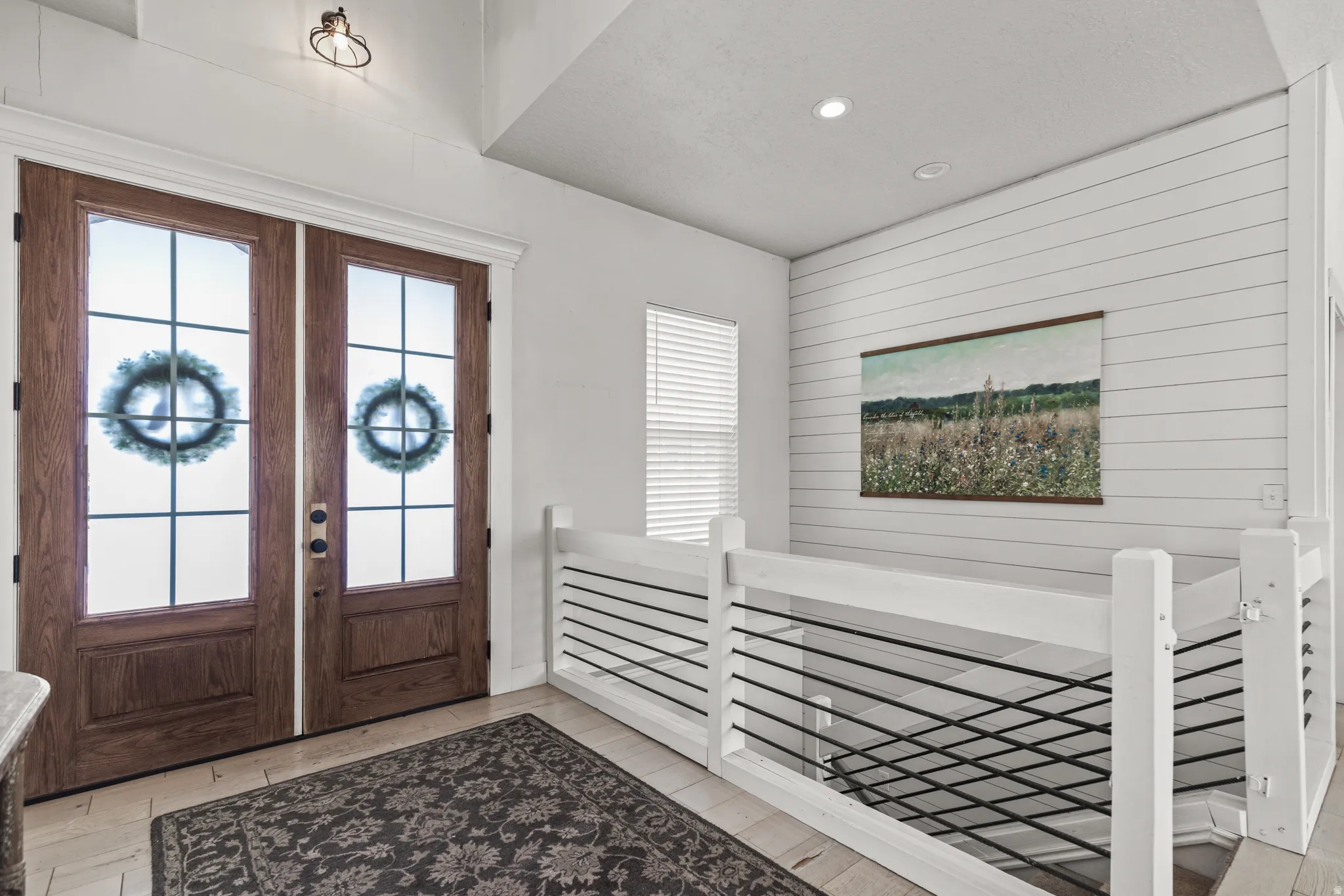 Foyer featuring french doors, wood walls, light wood-type flooring, and recessed lighting
