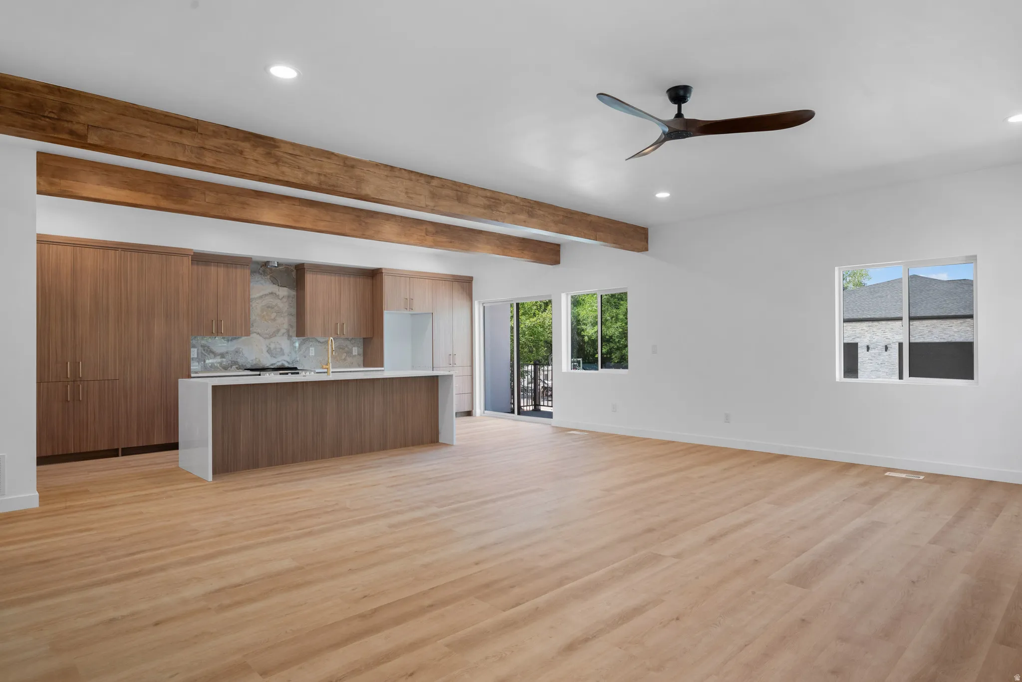 Open-concept living space with wood-finish flooring, exposed wood beams, and recessed lighting