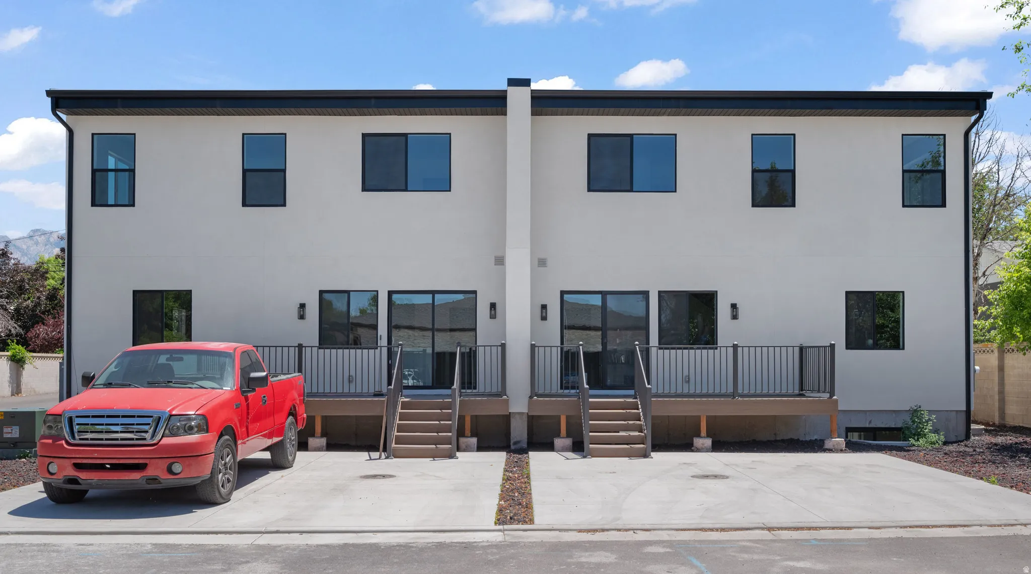 Contemporary exterior facade featuring light-colored stucco, black trim, and dark-framed windows