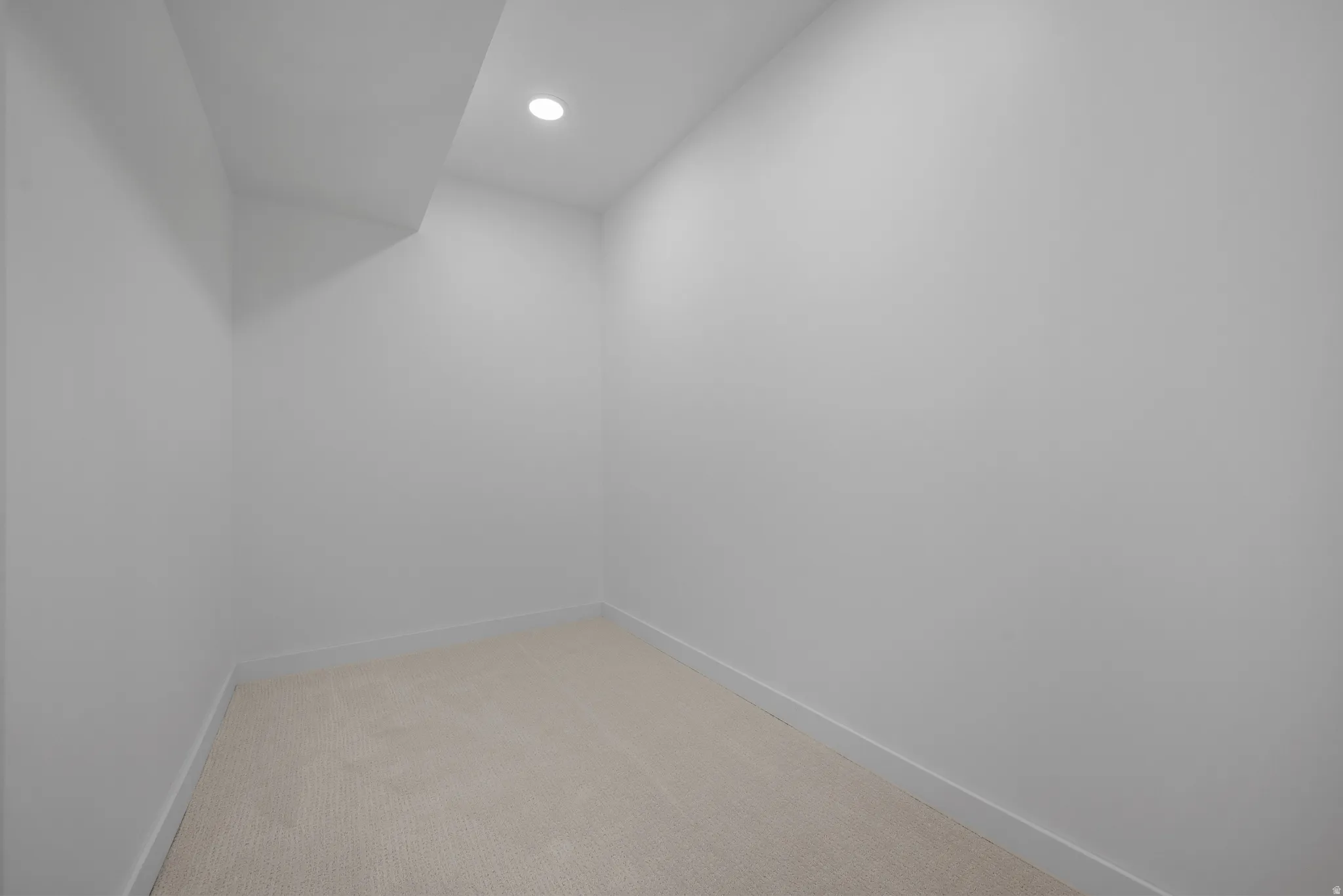 Compact interior space featuring neutral wall tones, recessed lighting, and light-toned carpeting