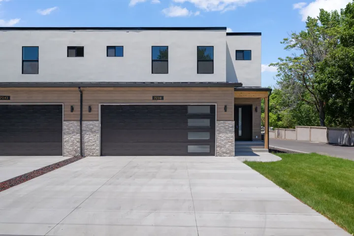 Modern facade featuring light-colored stucco and wood-finish siding