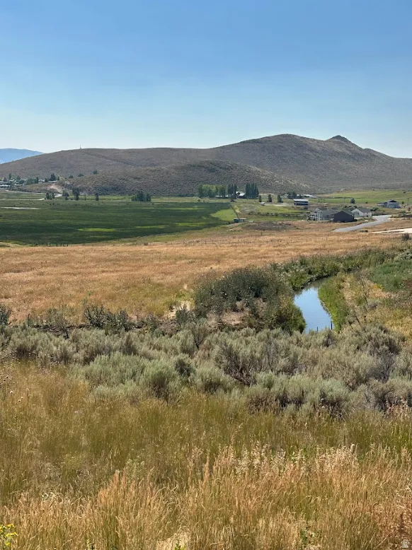 View of mountain backdrop with rural landscape and a large body of water