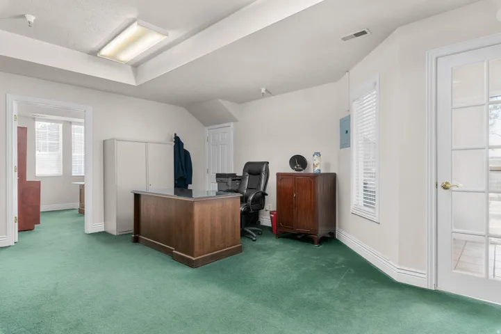 Home office with dark carpet and electric panel