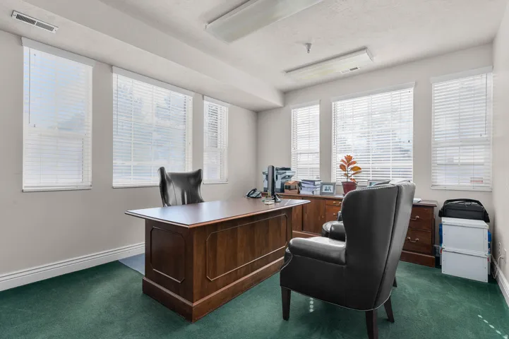 Office space featuring baseboards and dark carpet