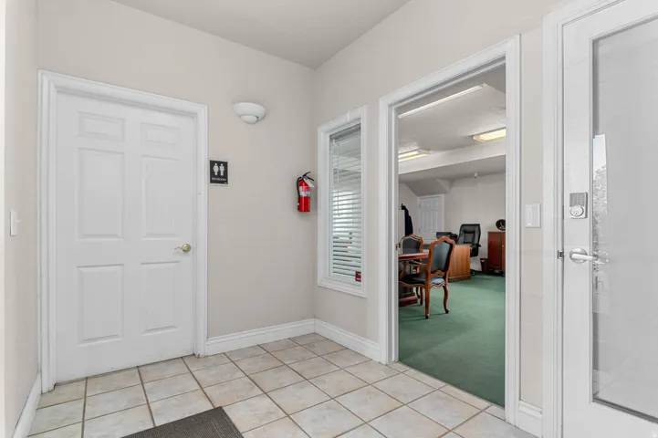 Entryway with light tile patterned floors and light colored carpet
