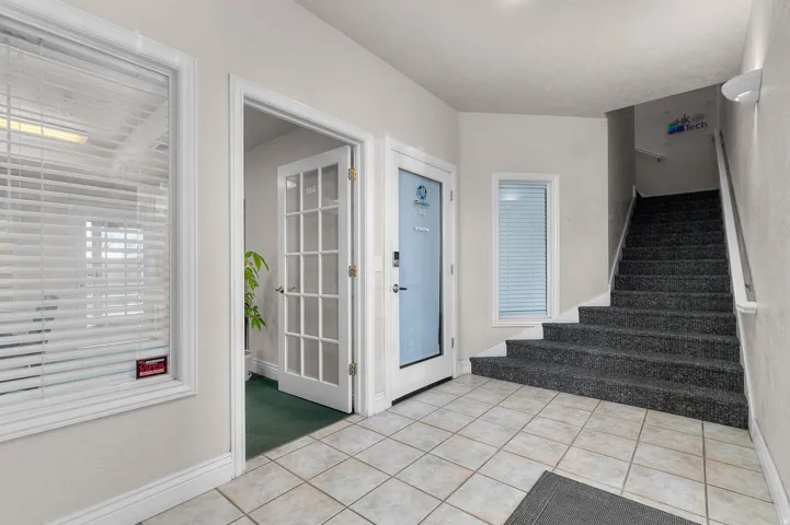 Entryway featuring light tile patterned floors and light carpet