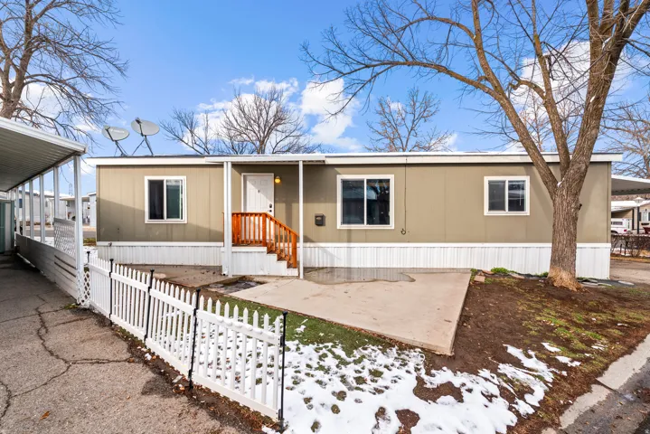 Manufactured / mobile home featuring a fenced front yard, a patio, and a carport