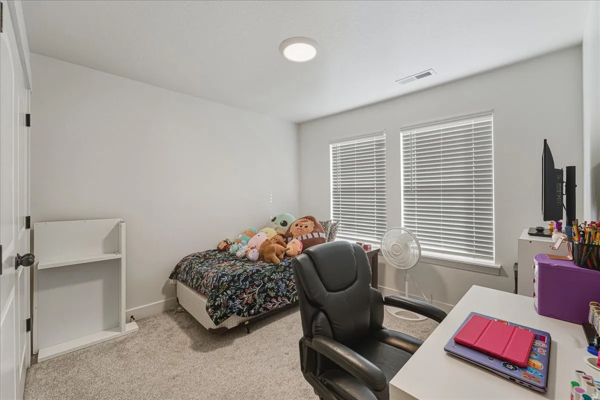 Bedroom with light carpet and an office area