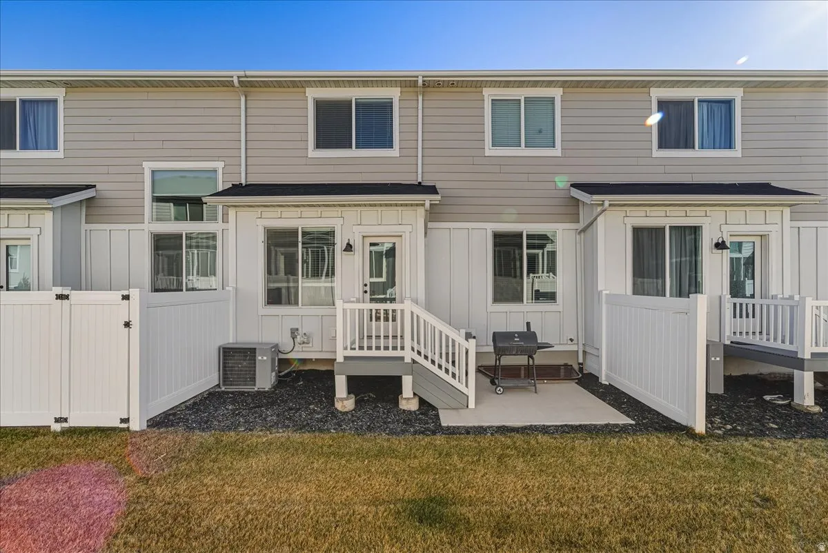 Back of property with a gate, a patio, a wooden deck, and board and batten siding