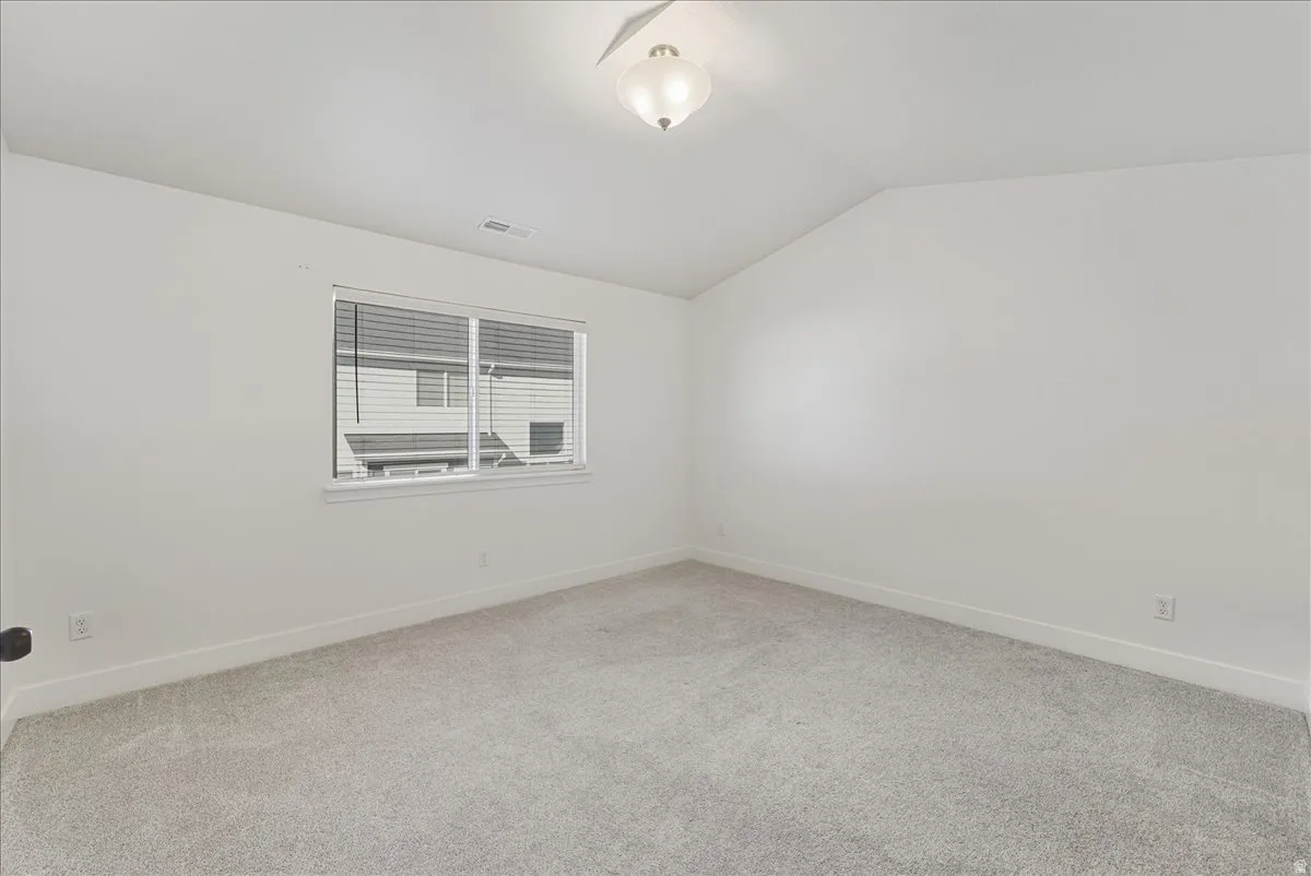 Empty room with light colored carpet and lofted ceiling