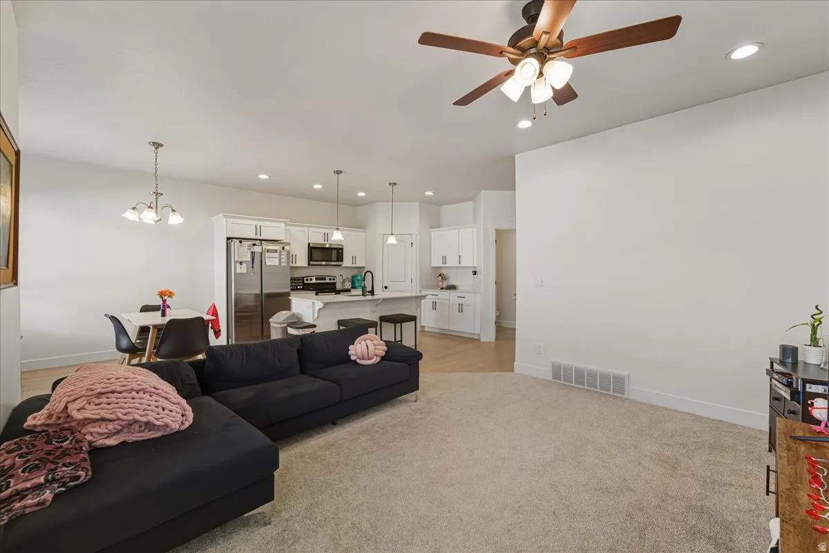 Living area with light carpet, a chandelier, and a ceiling fan