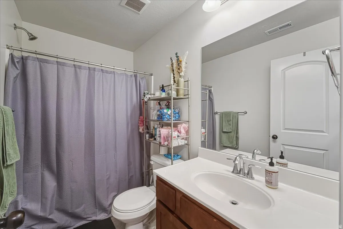 Bathroom featuring vanity, a textured ceiling, and shower / tub combo with curtain