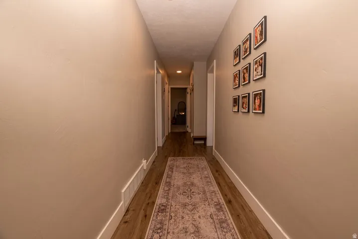 Hallway with baseboards and dark wood-type flooring