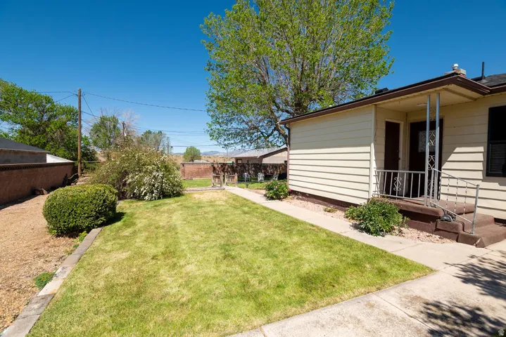 Front exterior featuring beige horizontal siding, a covered porch entry with metal railings, and a concrete walkway