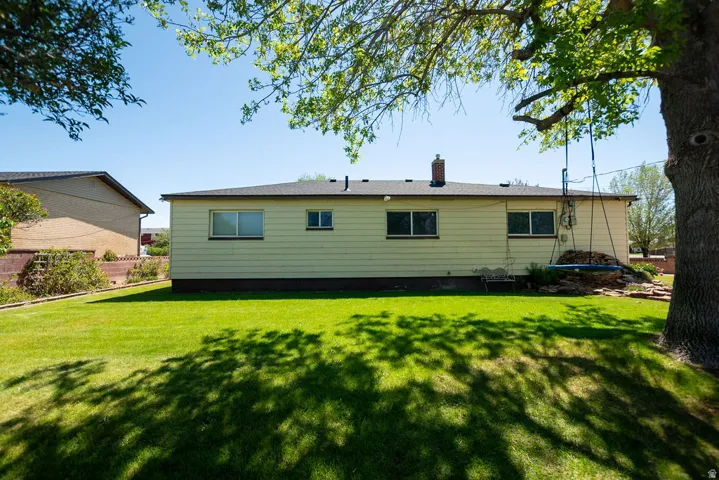 Expansive rear yard with a manicured lawn, established landscaping, and mature shade trees