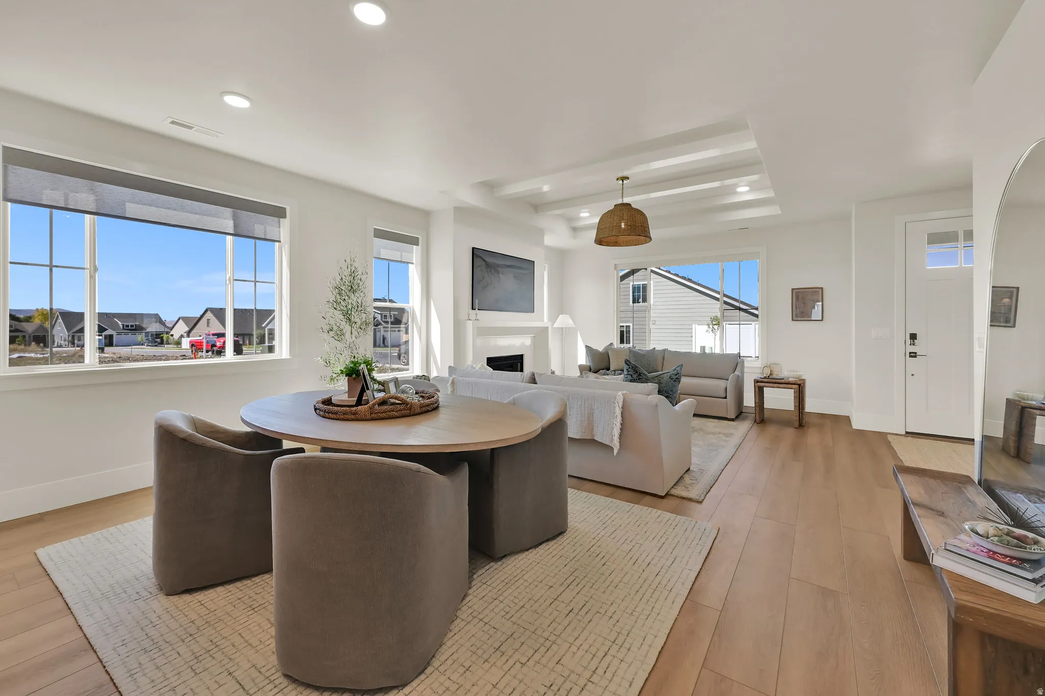 Dining space with light wood-style flooring, a tray ceiling, a fireplace, and recessed lighting