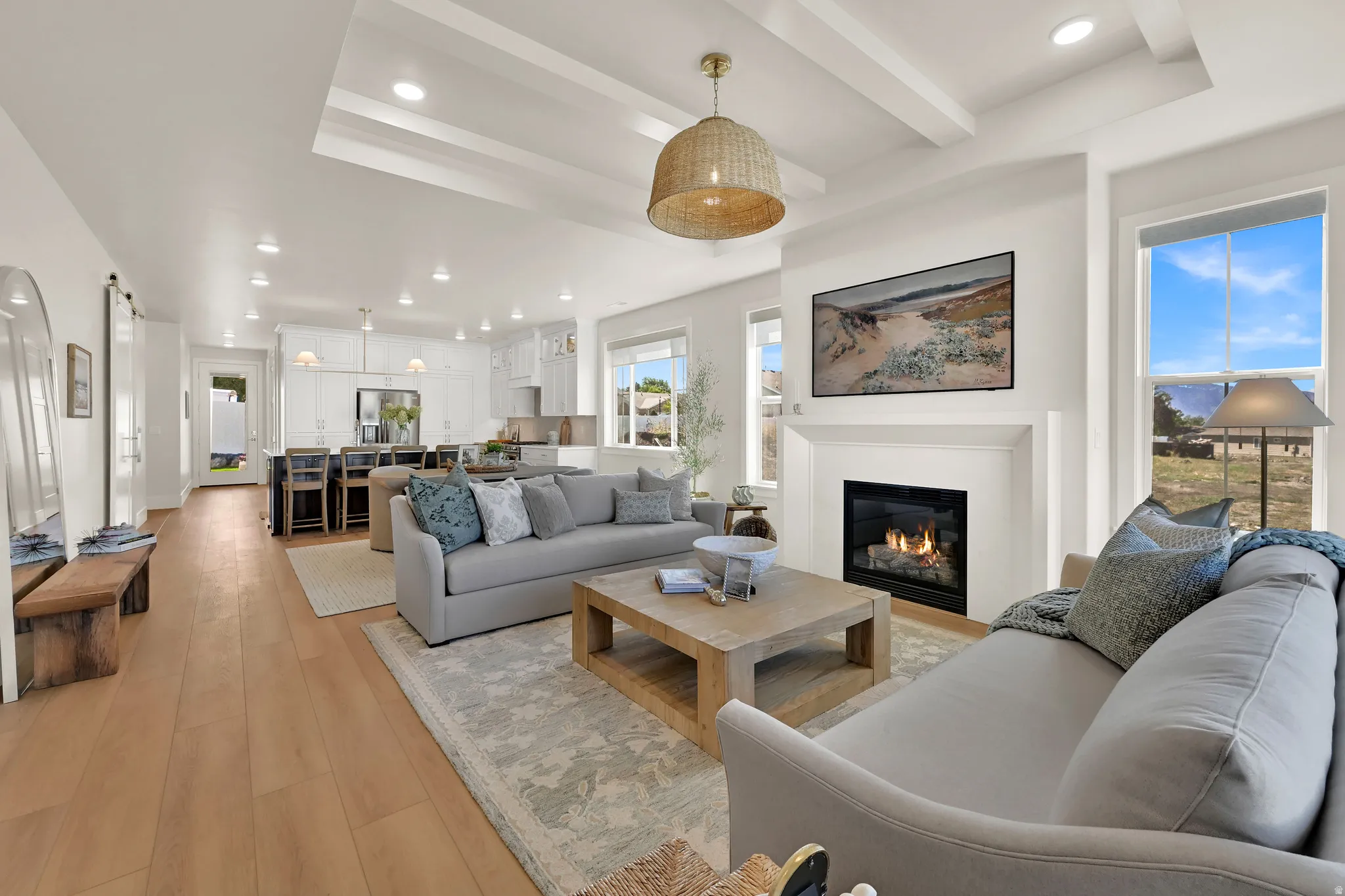 Living room with recessed lighting, a tray ceiling, light wood-style floors, and a glass covered fireplace