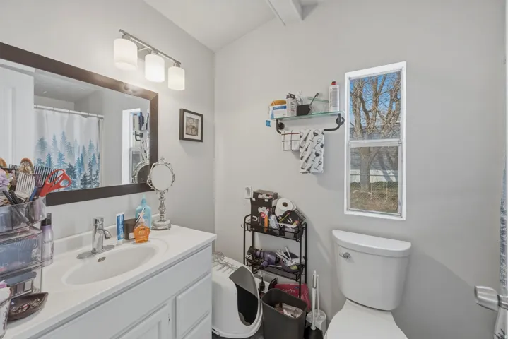 Full bath with vanity, curtained shower, and lofted ceiling with beams