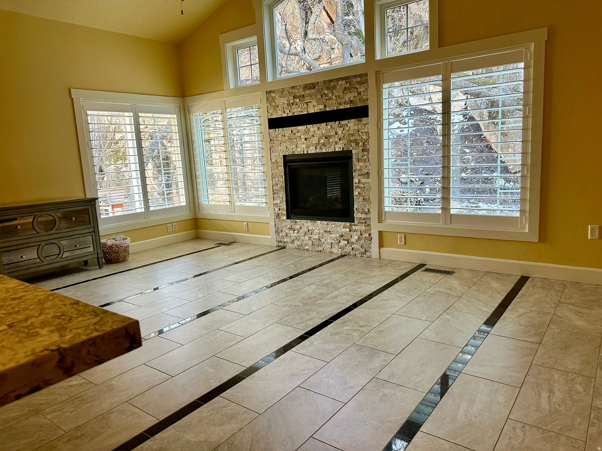 Unfurnished living room featuring vaulted ceiling, a fireplace, and inlaid floor details