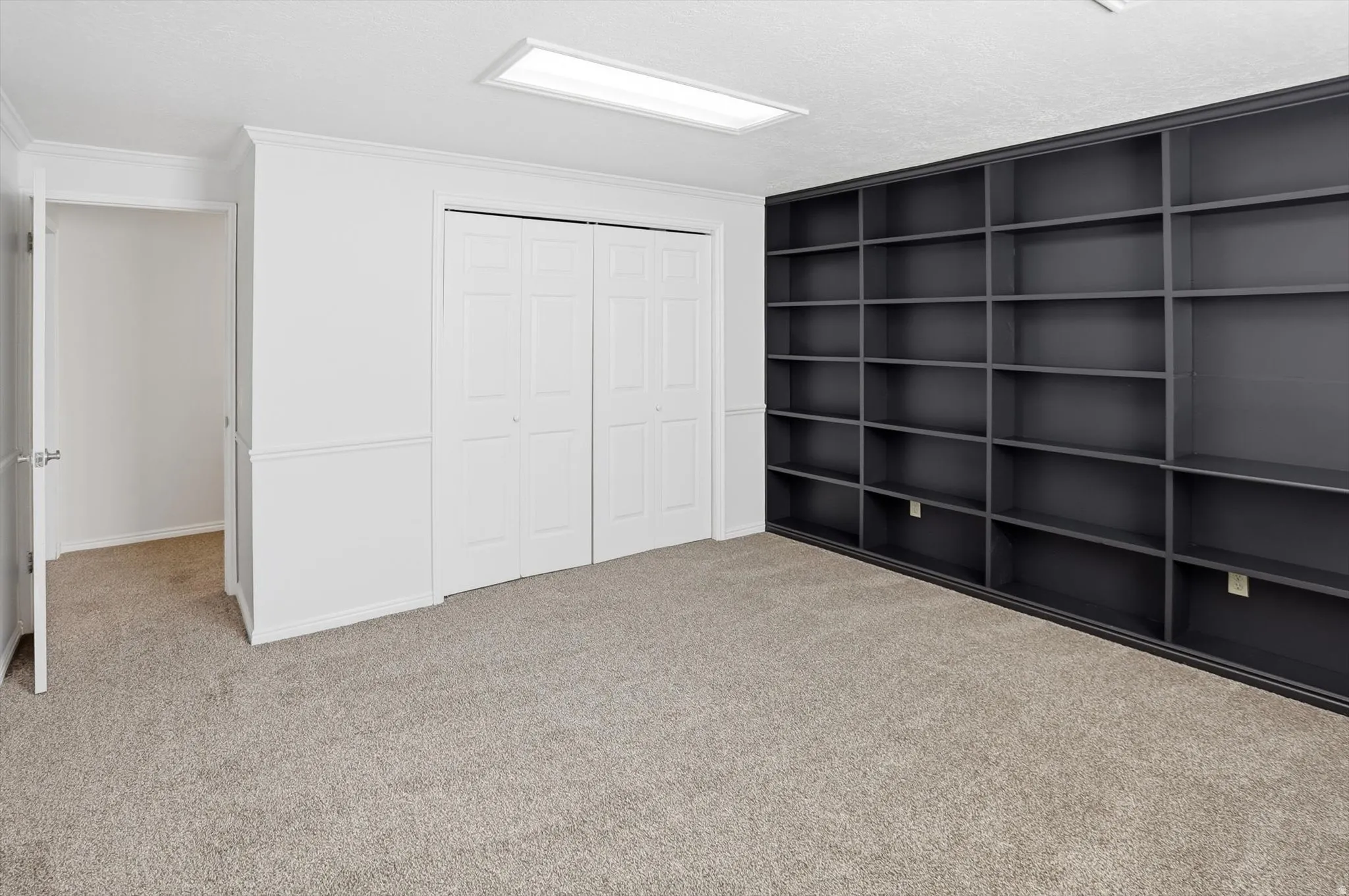 Unfurnished bedroom featuring light carpet, a closet, and crown molding