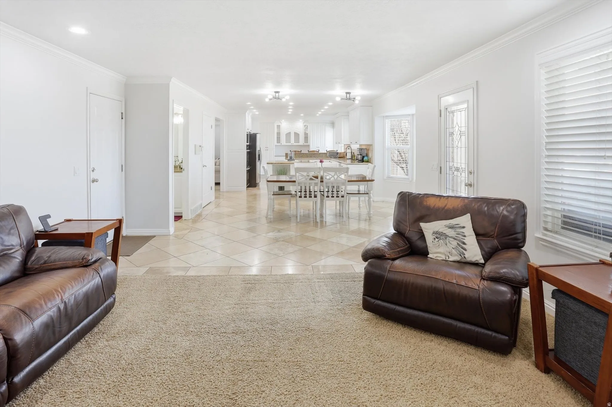 Living room with crown molding, light carpet, and light tile patterned floors