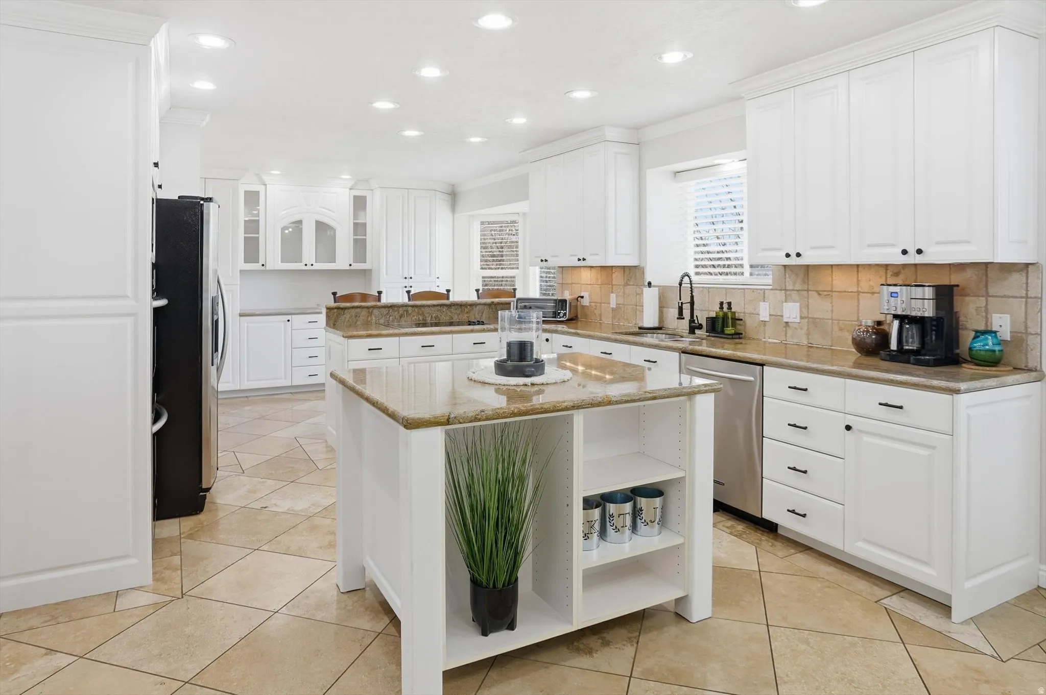 Kitchen featuring white cabinetry, glass fronted cabinets, open shelves, ornamental molding, and a kitchen island