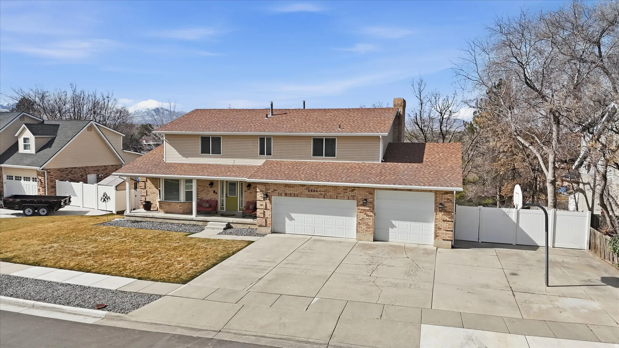 Traditional-style home with covered porch, roof with shingles, concrete driveway, and brick siding