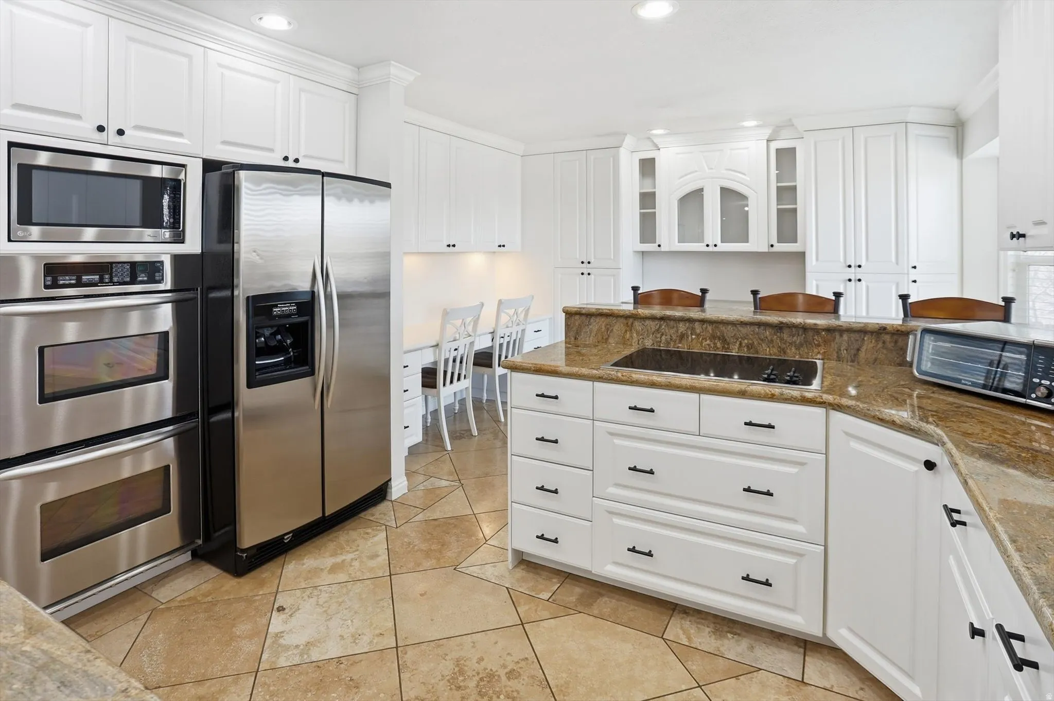 Kitchen with white cabinetry, stainless steel appliances, recessed lighting, glass insert cabinets, and dark stone counters