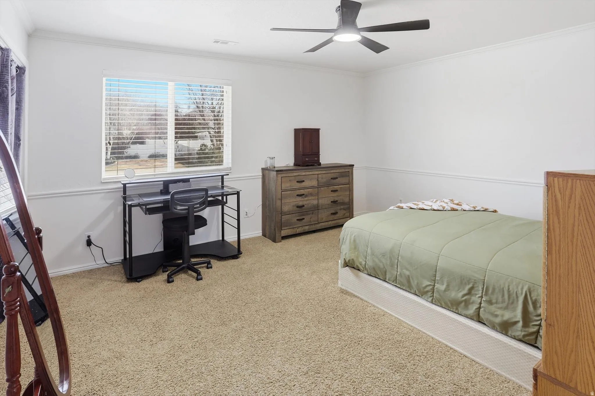 Carpeted bedroom featuring ornamental molding, ceiling fan, and an office area