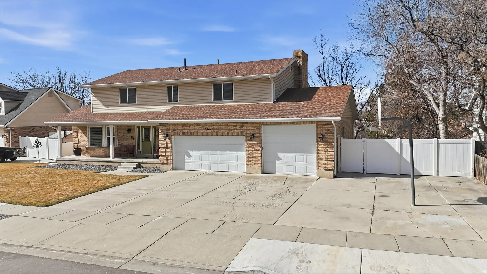 Traditional home featuring a porch, concrete driveway, a shingled roof, and brick siding